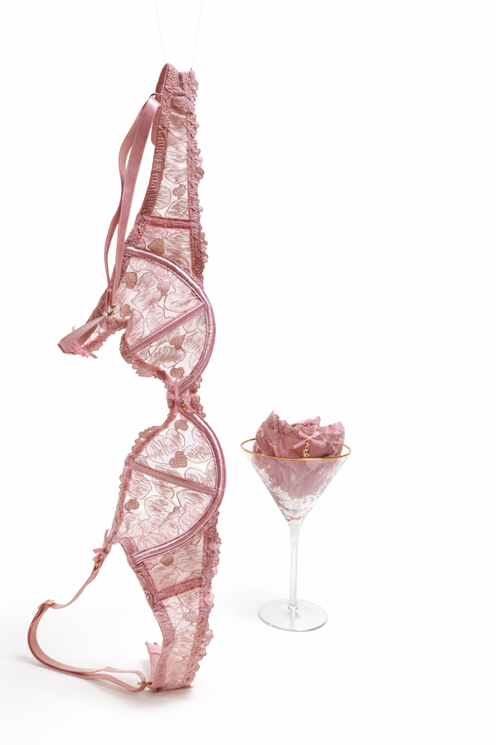 Pink lace lingerie set with a panty in cocktail glass on a white background