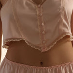 Light pink satin lingerie set with buttons and lace details.