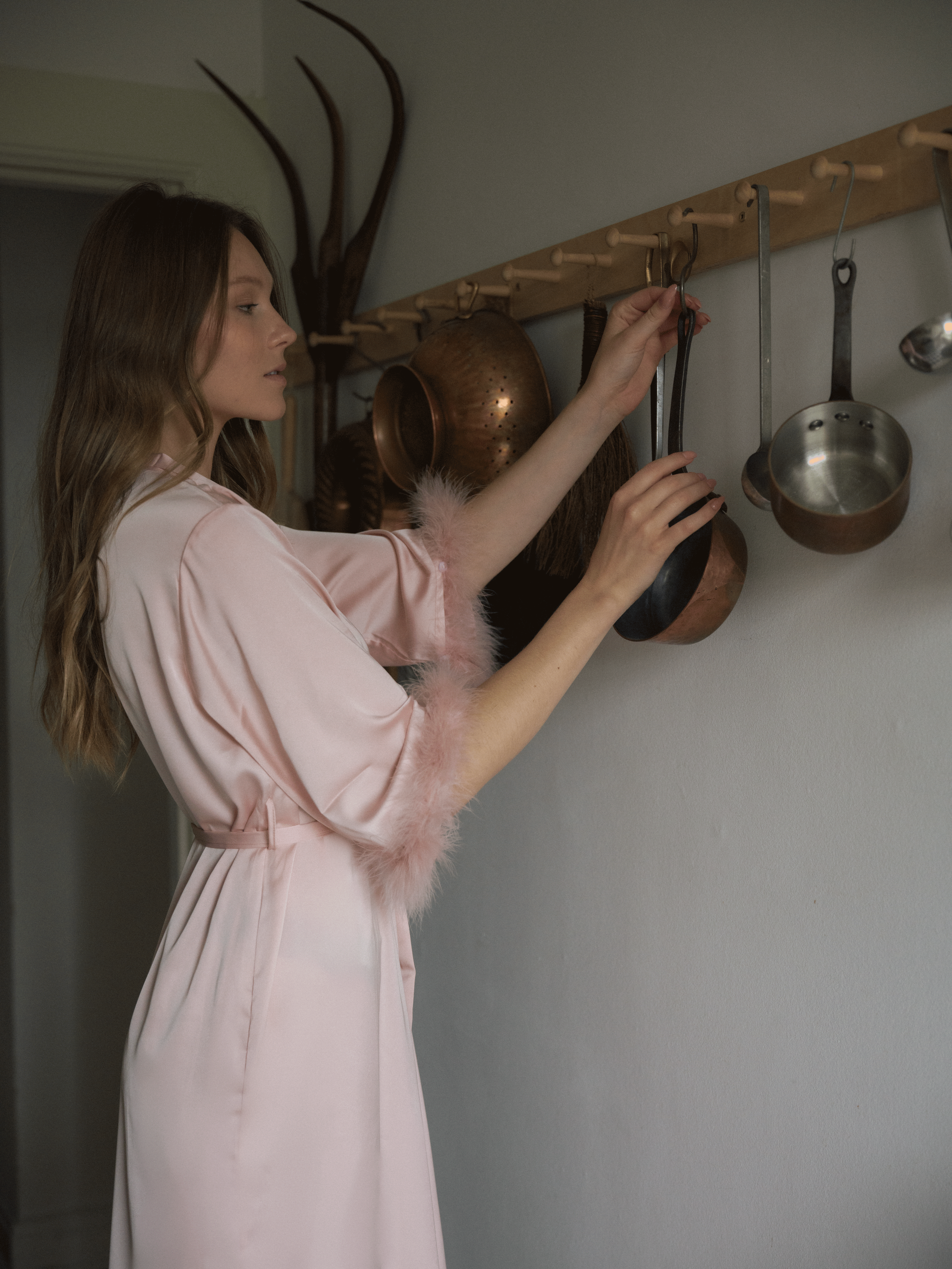 woman wearing feature a pink robe in kitchen cleaning up 