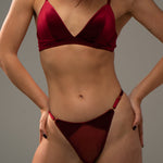 Woman wearing a red velvet lingerie against a grey background