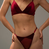 Woman wearing a red velvet lingerie against a grey background