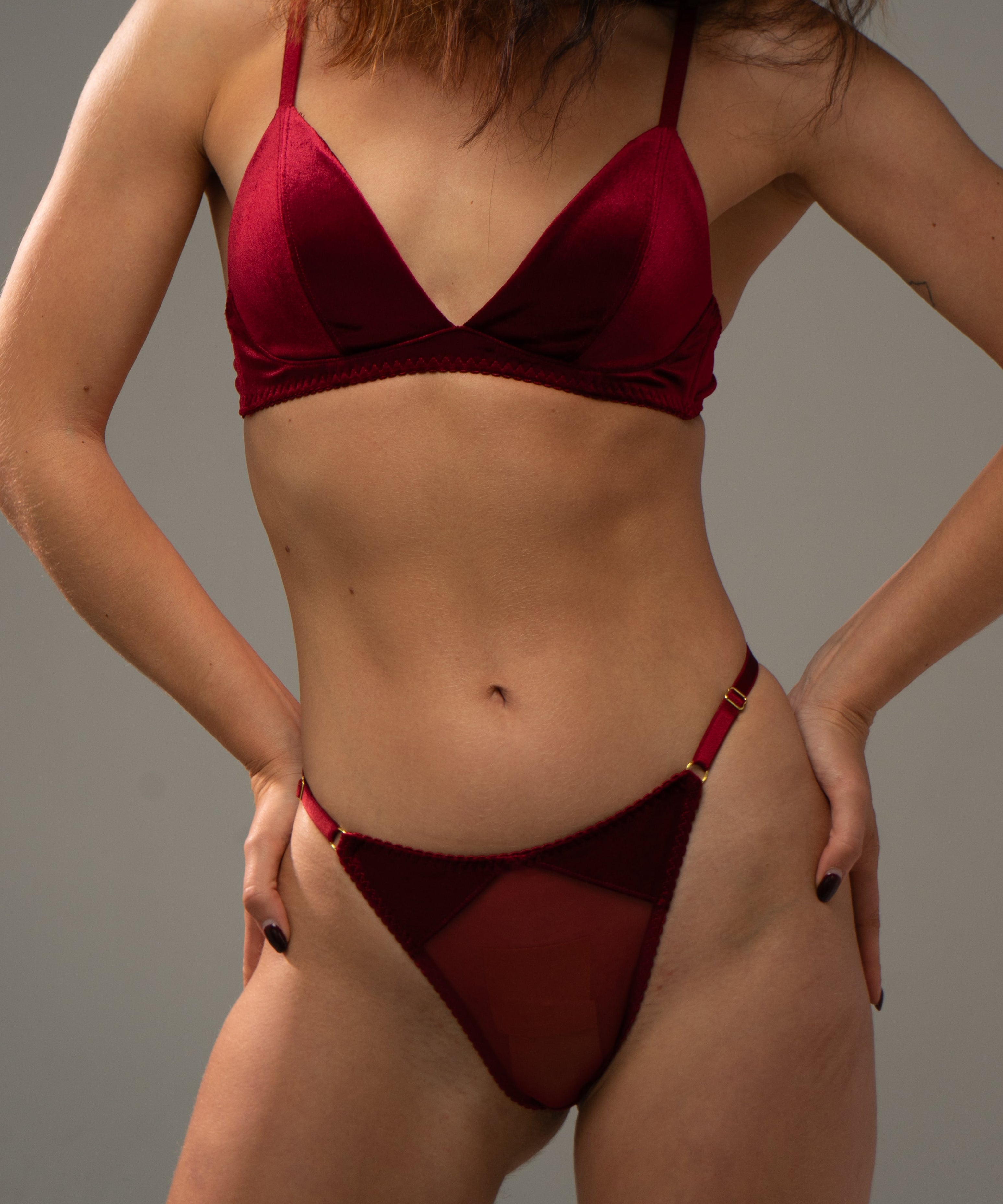 Woman wearing a red velvet lingerie against a grey background