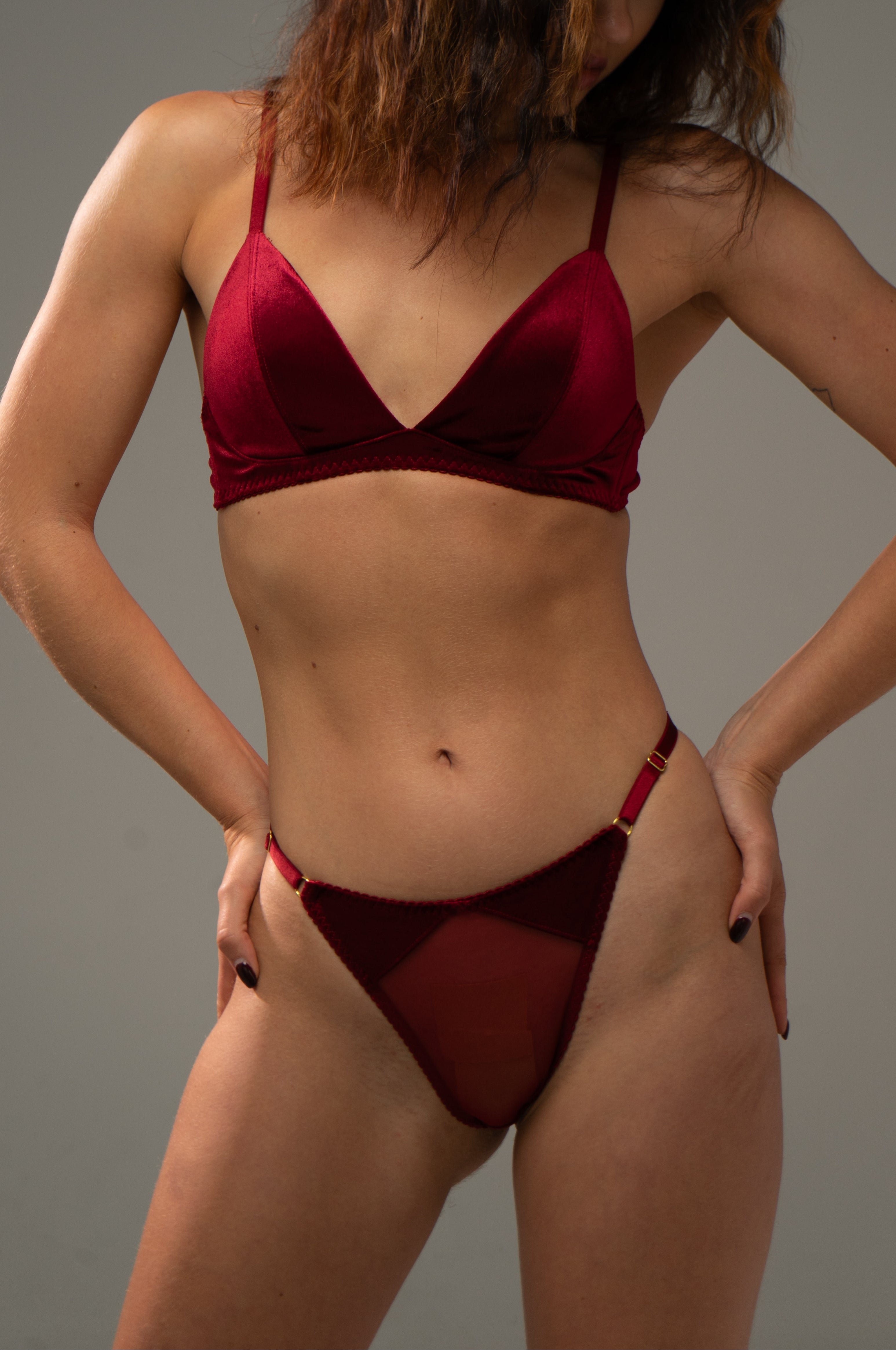 Woman wearing a red velvet lingerie against a grey background