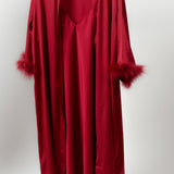 a model wearing silky red robe with feather trimmed cuffs still life image