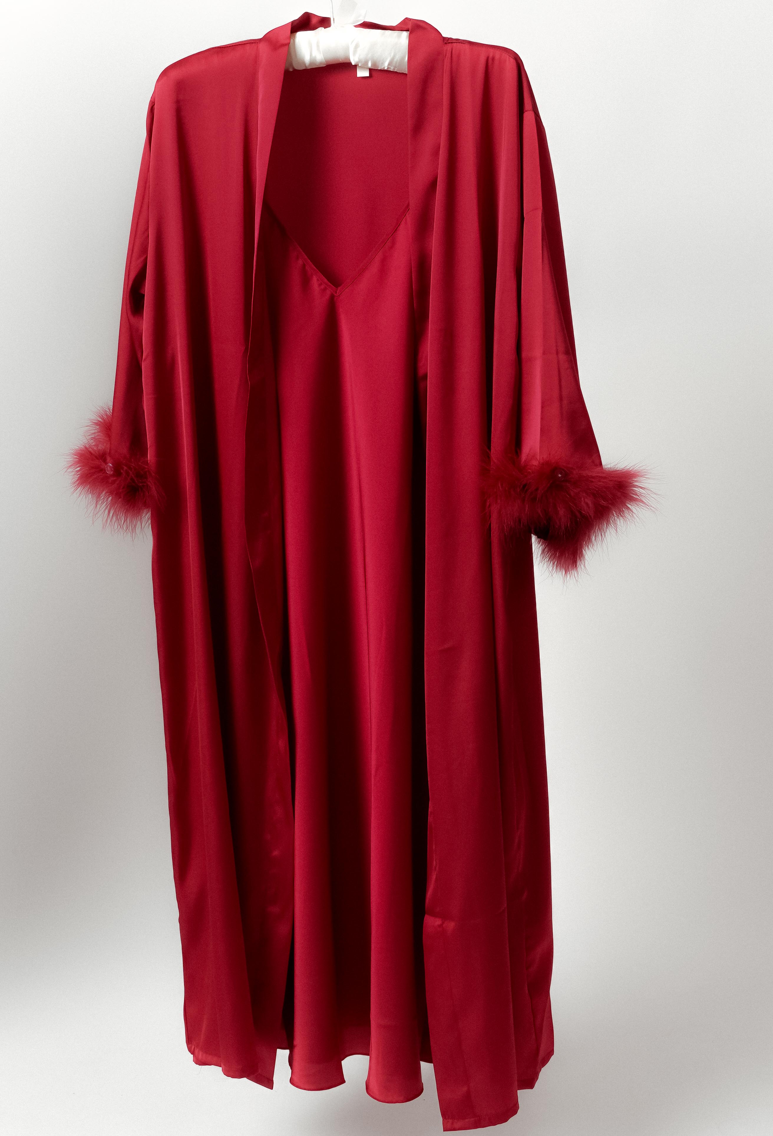a model wearing silky red robe with feather trimmed cuffs still life image