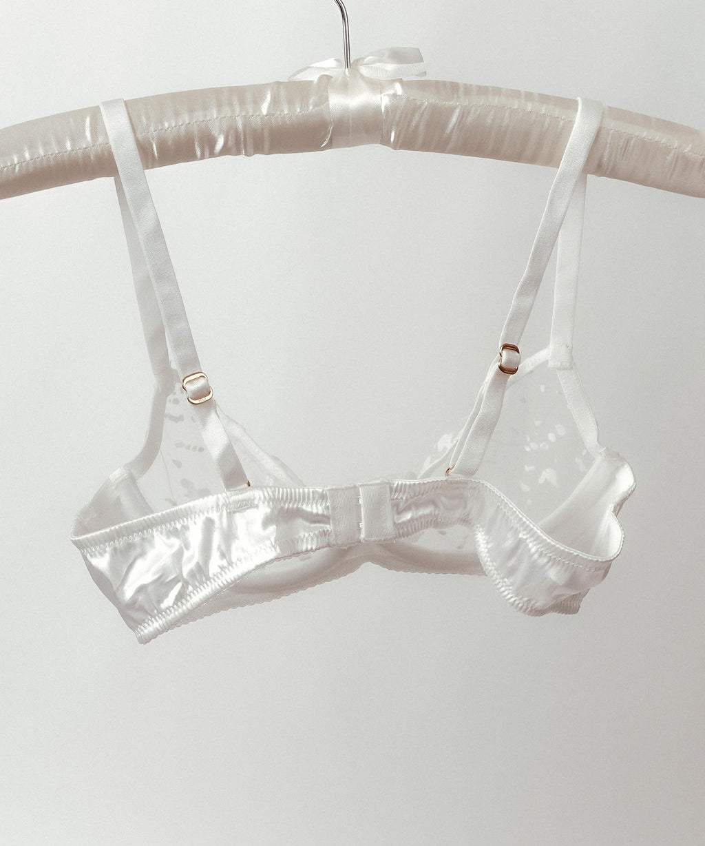 Clear plastic bra on a hanger against a white background