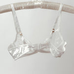 Clear plastic bra on a hanger against a white background