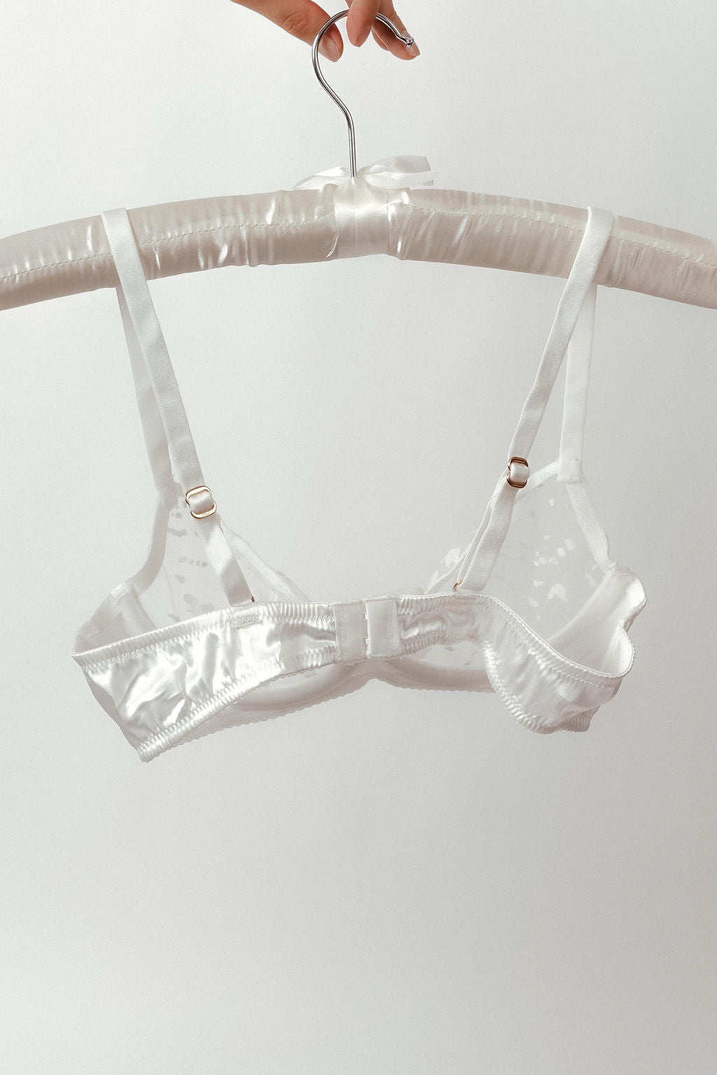 Clear plastic bra on a hanger against a white background